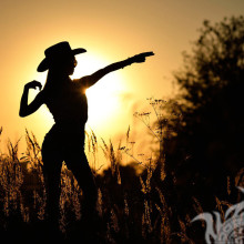 Girl in a cowboy hat on a background of sunset for page
