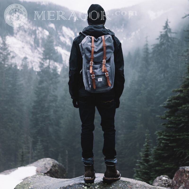 Un chico con una mochila en la foto de las montañas desde atrás. De atrás
