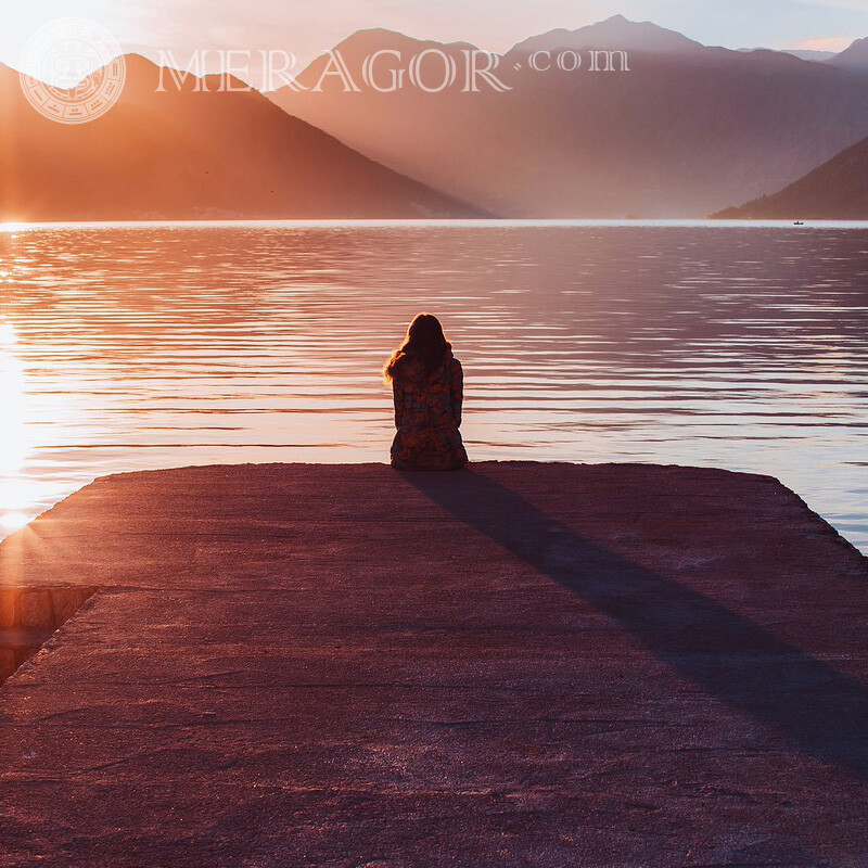 Mädchen, das auf der Ufereinsamkeit auf der Seite sitzt Silhouette Traurige