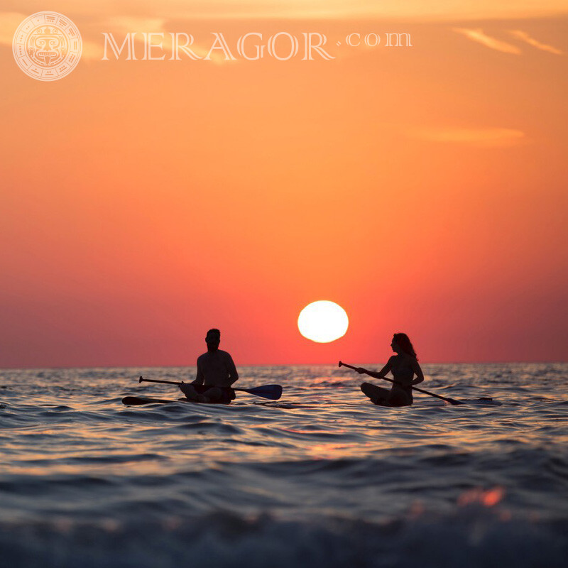 Un gars et une fille avec des rames au coucher du soleil sur un réseau social Silhouette Mec avec une fille