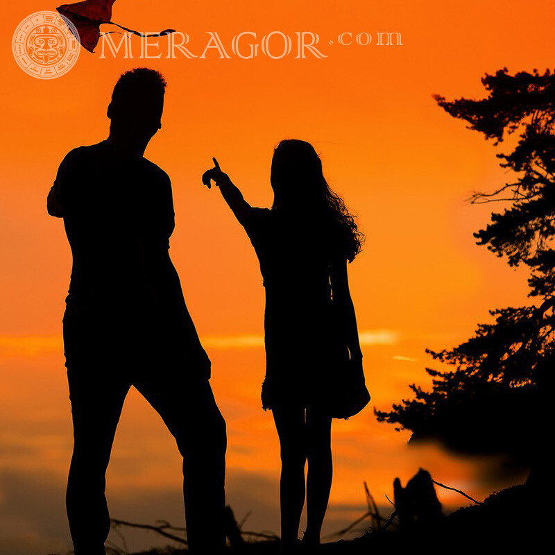 Laufender Drachensonnenuntergang auf Rechnung Silhouette Mann mit Freundin